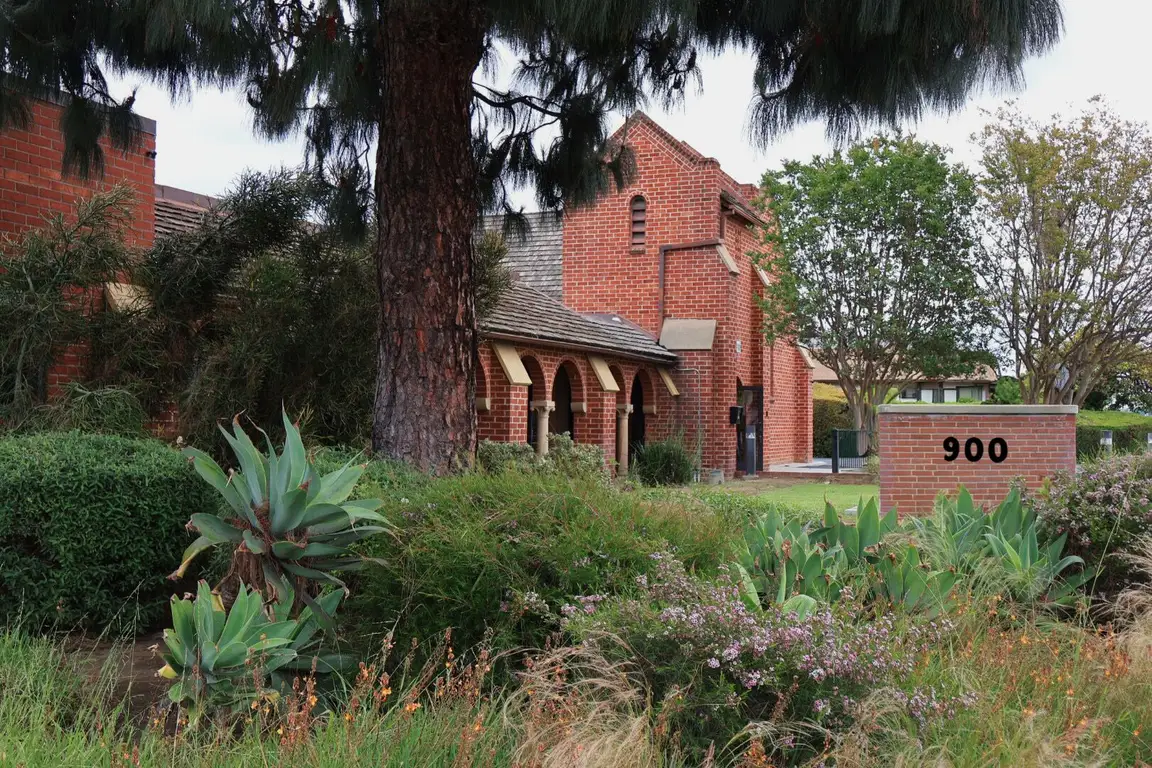 Front view of the Social Club 900 brick building with the 900 monument sign and landscaped garden in Alhambra