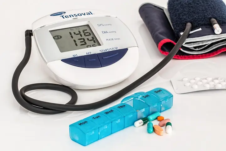 A home blood-pressure monitor beside a weekly pill organizer