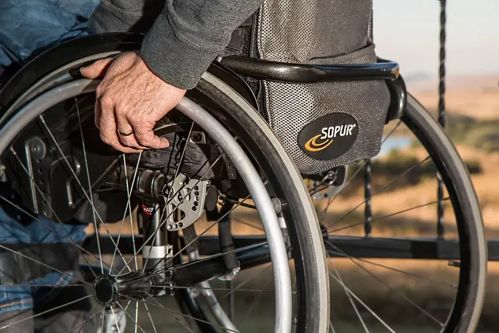A close-up of a person using a manual wheelchair outdoors